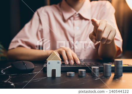 Businesswoman Analyzing Financial Data with Model House and Coins on Desk for Real Estate Investment Concept Businesswoman Analyzing Financial Data with Model House and Coins on Desk for Real Estate Investment Concept 140544122