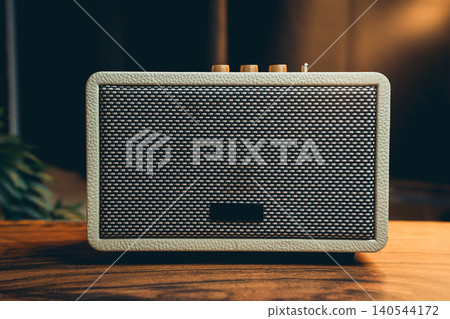 Vintage style speakers. Vintage Style Wireless Speaker with Textured Surface and Knobs on Wooden Table in Cozy Interior Setting Vintage style speakers. Vintage Style Wireless Speaker with Textured Surface and Knobs on Wooden Table in Cozy Interior Setting 140544172