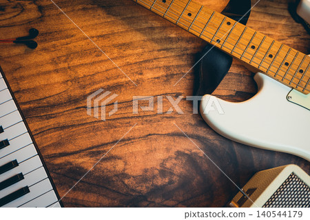 Music background concept. Close-up View of Guitar, Piano Keys, and Music Equipment on Wooden Table Surface for Creative Background 140544179