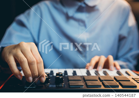 Pianist concept. Close-Up of a Music Producer Adjusting Controls on a MIDI Keyboard in a Home Studio Setting Pianist concept. Close-Up of a Music Producer Adjusting Controls on a MIDI Keyboard in a Home Studio Setting 140544187