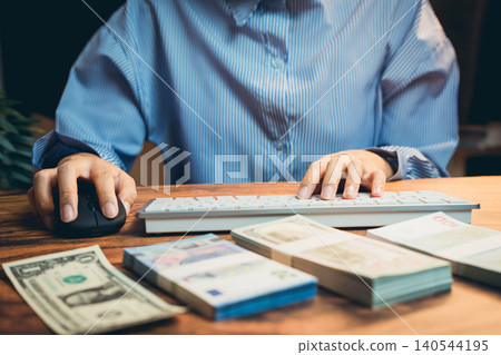 Business concept. Business Person Working Online with Banknotes and Financial Charts on Desk in Modern Office Environment Business concept. Business Person Working Online with Banknotes and Financial Charts on Desk in Modern Office Environment 140544195