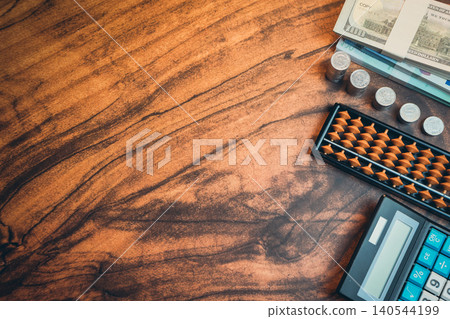 Business concept. Detailed View of a Wooden Workspace Featuring Currency, Coins, Calculator, and Abacus for Financial Analysis 140544199