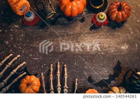 Halloween flat lay. Festive Halloween Decorations with Pumpkins, Candles, Skeletons, and Spooky Props on a Dark Wooden Surface 140544261