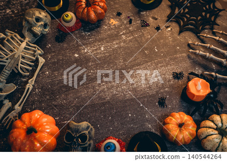 Halloween flat lay. Spooky Halloween Decorations with Skeleton, Pumpkins, Candles, and Creepy Props on Wooden Tabletop 140544264