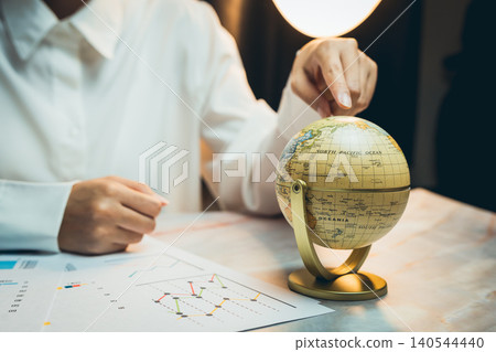 Business concept. Business Professional Examining Globe and Analyzing Graphs with Data Visualization in Modern Workspace 140544440