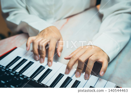 Pianist Concept. Close-Up Hands Playing Keyboard on Music Production Table in Modern Studio Environment Pianist Concept. Close-Up Hands Playing Keyboard on Music Production Table in Modern Studio Environment 140544463