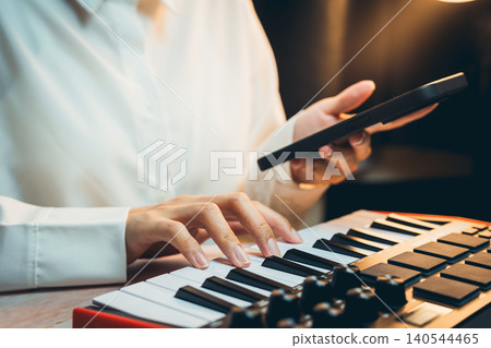 Pianist Concept. Musician Creating Beats with Keyboard and Phone in a Cozy Studio Setting, Focus on Hands and Instruments Pianist Concept. Musician Creating Beats with Keyboard and Phone in a Cozy Studio Setting, Focus on Hands and Instruments 140544465