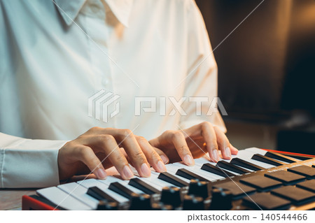 Pianist Concept. A Music Producer Working on a Keyboard Synthesizer in a Dimly Lit Studio Setting Pianist Concept. A Music Producer Working on a Keyboard Synthesizer in a Dimly Lit Studio Setting 140544466