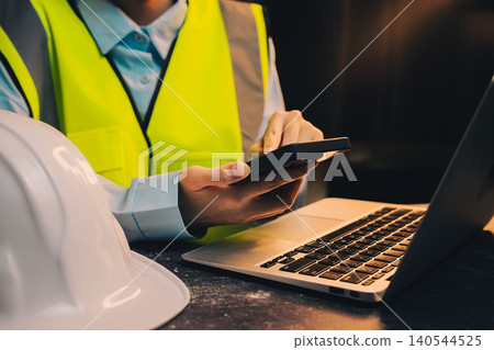 Engineer concept. Construction Worker Using Mobile Device for Project Management in Office Setting During Daylight Hours Engineer concept. Construction Worker Using Mobile Device for Project Management in Office Setting During Daylight Hours 140544525