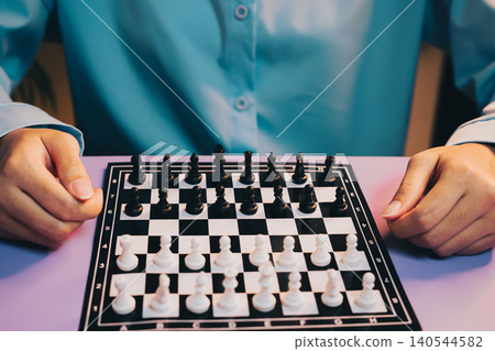 Chess Game. Focused Player Engaging in Strategic Game of Chess with Black and White Pieces on Colorful Board Chess Game. Focused Player Engaging in Strategic Game of Chess with Black and White Pieces on Colorful Board 140544582