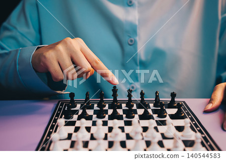 Chess Game. Focused Hand of Player Pointing at Black Chess Piece on a Board During Competitive Game Match Chess Game. Focused Hand of Player Pointing at Black Chess Piece on a Board During Competitive Game Match 140544583