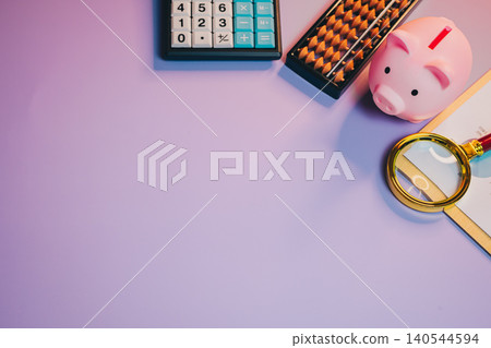 Business flat lay. Financial Planning Tools with Piggy Bank, Calculator, Abacus, and Notebook on Purple Background for Savings Concept Business flat lay. Financial Planning Tools with Piggy Bank, Calculator, Abacus, and Notebook on Purple Background for Savings Concept 140544594