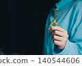 Success key concept. Elegant Gold Key Held by Hand in Soft Focus Setting with Dark Background, Symbolizing Unlocking Opportunities 140544606