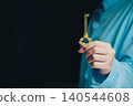 Success key concept. Elegant hand holding a vintage golden key against a dark background, symbolizing secrets and opportunities 140544608