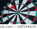 Business Target concept. Close-Up View of a Dartboard with a Red Dart Stuck in the Bullseye Against a Dark Background 140544614