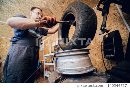 Professional car mechanic replace tire on wheel. Cleaning disc Professional car mechanic replace tire on wheel. Cleaning disc 140544757