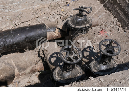 Old underground water pipeline with metal gate valves exposed during excavation and maintenance work Old underground water pipeline with metal gate valves exposed during excavation and maintenance work 140544854
