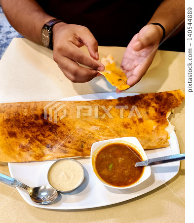 Man Eating South Indian Dosa in a Restaurant Man Eating South Indian Dosa in a Restaurant 140544889