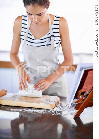 Female person, wheat or dough in kitchen to bake bread with apron and flour on counter. Woman, bakery and cookbook for recipe or ingredients, roller and board to make pastry at home or house Female person, wheat or dough in kitchen to bake bread with apron and flour on counter. Woman, bakery and cookbook for recipe or ingredients, roller and board to make pastry at home or house 140545179