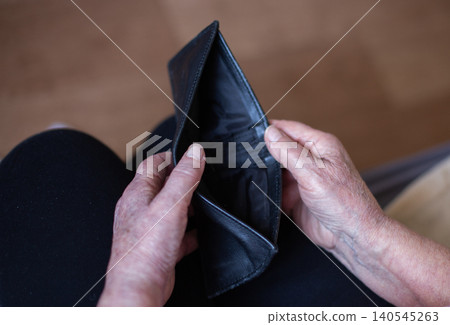 Senior person holding empty wallet showing financial hardship Senior person holding empty wallet showing financial hardship 140545263