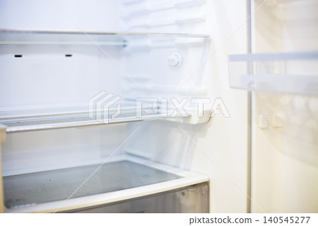 Empty refrigerator interior showing white shelves and lack of food 140545277