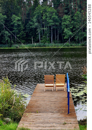 Wooden chairs on pier by tranquil lake forest Wooden chairs on pier by tranquil lake forest 140545288