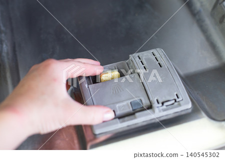 Hand placing detergent tablet in dishwasher dispenser Hand placing detergent tablet in dishwasher dispenser 140545302
