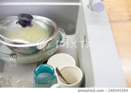 Dirty dishes piling up in kitchen sink Dirty dishes piling up in kitchen sink 140545304