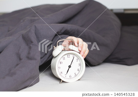 Sleeping person lying on the bed in bedroom and stopping alarm clock Sleeping person lying on the bed in bedroom and stopping alarm clock 140545328