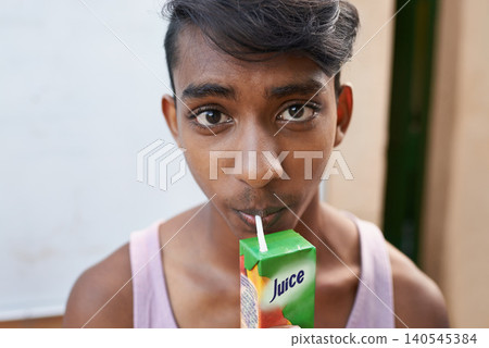 Portrait, teenager and drinking juice outdoor for healthy diet, wellness or nutrition in India. Face, boy and beverage with straw in box for benefits, energy and organic liquid fruit for hydration Portrait, teenager and drinking juice outdoor for healthy diet, wellness or nutrition in India. Face, boy and beverage with straw in box for benefits, energy and organic liquid fruit for hydration 140545384