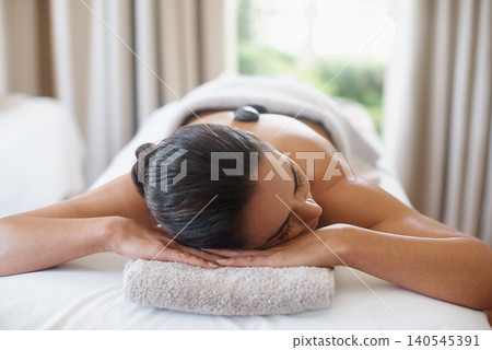 Relax, hot stone and woman at spa for massage, peace and calm for skincare at luxury resort. Beauty, therapy and person at salon with rocks on back for body treatment, health or rest for wellness Relax, hot stone and woman at spa for massage, peace and calm for skincare at luxury resort. Beauty, therapy and person at salon with rocks on back for body treatment, health or rest for wellness 140545391