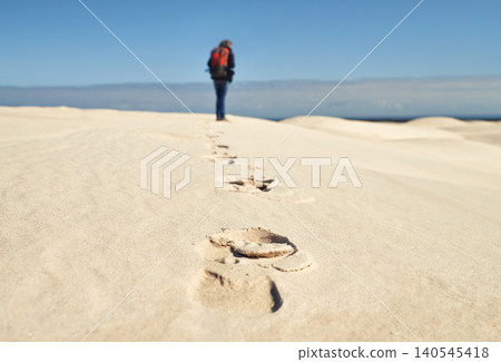 Person, hiking and walking on sand dunes for fitness adventure in desert and extreme sport in arid climate. Athlete, back or survival gear for nature exploration, footprints or wanderlust vacation Person, hiking and walking on sand dunes for fitness adventure in desert and extreme sport in arid climate. Athlete, back or survival gear for nature exploration, footprints or wanderlust vacation 140545418
