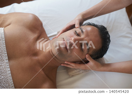 Hands, head massage and top view of man at salon for skincare, peace and calm at luxury resort at table for wellness. Above, therapy and masseuse at spa for face treatment, health and person relax Hands, head massage and top view of man at salon for skincare, peace and calm at luxury resort at table for wellness. Above, therapy and masseuse at spa for face treatment, health and person relax 140545420