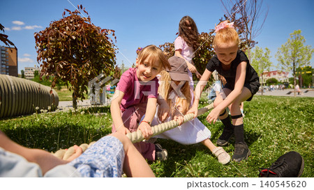 Young children pulling rope in outdoor tug of war game. Young children pulling rope in outdoor tug of war game. 140545620