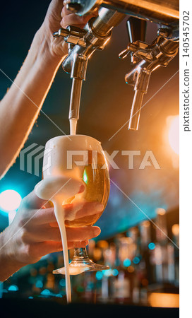 Female hand holding foamy beer glass under draft tap in bar. Female hand holding foamy beer glass under draft tap in bar. 140545702