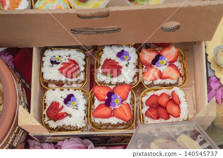Strawberry cakes with cream, edible flowers sit in boxes, Kazanluk Rose Festival food event. Cake display with bakery craft, dessert market, berries, sweets, Bulgarian cuisine 140545737