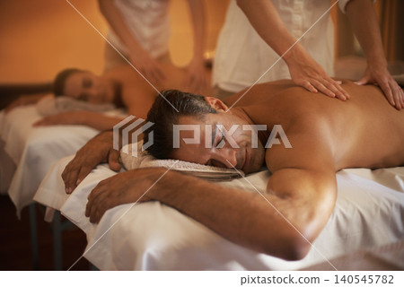Couple, massage and treatment at spa with masseuse, wellness and zen for body care at luxury resort. Physical therapy, detox and holistic healing with people for stress relief, peace and service 140545782