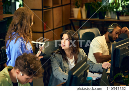 Businesswoman discussing work tasks with colleague at computer. Businesswoman discussing work tasks with colleague at computer. 140545862