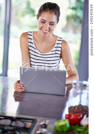 Woman, happy and laptop on kitchen counter, female person and home on internet. Browsing, cooking and recipes on social media, online search with technology for organic and healthy food ideas 140545934