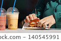 Hands holding gourmet burger with fruit smoothies at food festival in Karlin 140545991
