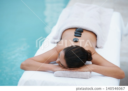 Relax, hot stone massage and woman at pool at spa for health, zen wellness and luxury holistic treatment. Self care, peace and girl on table for body therapy, comfort and calm pamper service at hotel 140546067