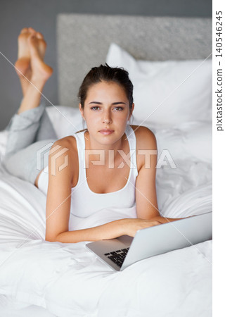 Woman, lying and laptop on bed in portrait for connection, typing and chatting online to relax. Female person, technology and computer for conversation in casual outfit and comfortable in bedroom Woman, lying and laptop on bed in portrait for connection, typing and chatting online to relax. Female person, technology and computer for conversation in casual outfit and comfortable in bedroom 140546245