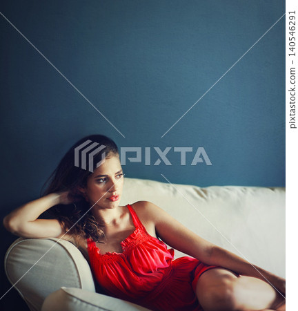 Relax, sexy and space with woman on sofa in studio on blue background for feminine wellness. Beauty, fashion and thinking with confident or serious young person in red dress for valentines day Relax, sexy and space with woman on sofa in studio on blue background for feminine wellness. Beauty, fashion and thinking with confident or serious young person in red dress for valentines day 140546291