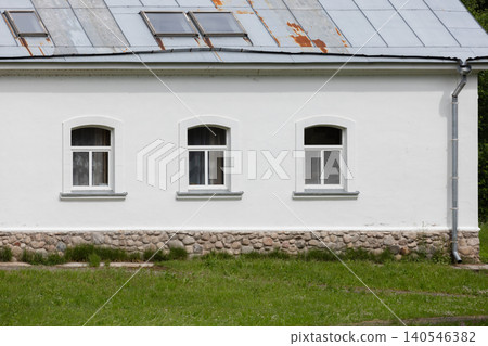 A simple white country house facade featuring three arched windows 140546382