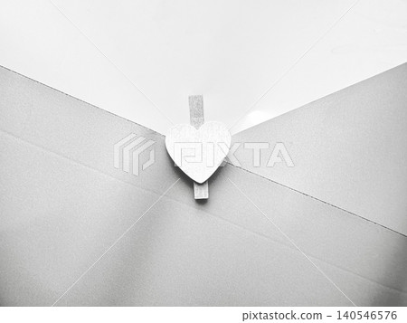 wooden heart clothespin clipped to white envelope flap in minimalist monochrome closeup with soft shadows wooden heart clothespin clipped to white envelope flap in minimalist monochrome closeup with soft shadows 140546576