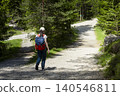 Woman hiker with a backpack at a crossroads in a forest, highlighting connection with nature through physical activity 140546811
