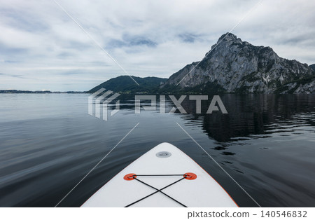 First person view from a white stand up paddleboard on calm lake Traunsee in the Austrian Alps, capturing summer water activity. First person view from a white stand up paddleboard on calm lake Traunsee in the Austrian Alps, capturing summer water activity. 140546832