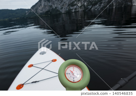 Hand holding a compass over Lake Traunsee with the Austrian Alps in the background, evoking universal freedom and open horizons. Hand holding a compass over Lake Traunsee with the Austrian Alps in the background, evoking universal freedom and open horizons. 140546835