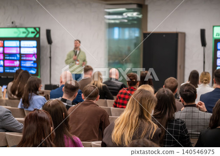 Business conference presentation with speaker addressing attentive audience in modern meeting room setting Business conference presentation with speaker addressing attentive audience in modern meeting room setting 140546975