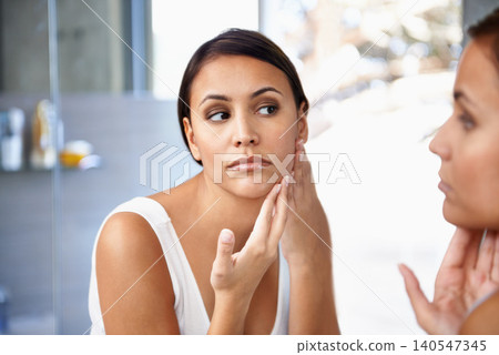 Worried, woman and skincare in mirror pimple or face spot or acne on cheek. Female person, unhappy or sad and reflection in bathroom for lotion, self care and glowing skin as daily routine Worried, woman and skincare in mirror pimple or face spot or acne on cheek. Female person, unhappy or sad and reflection in bathroom for lotion, self care and glowing skin as daily routine 140547345